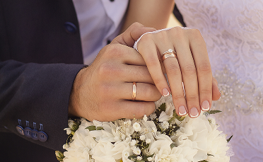 Close-up of a bride and groom’s hands showing their wedding rings.